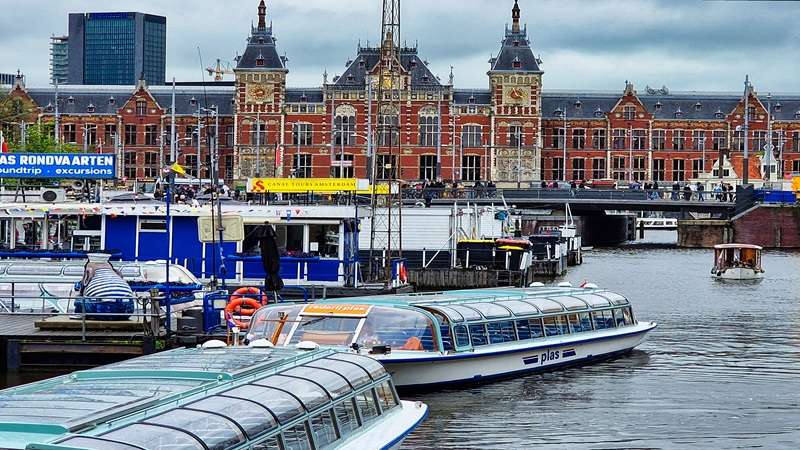 Widok na kanał Amsterdamu oraz Plac Dworcowy z zabytkowym budynkiem Amsterdam Centraal Station