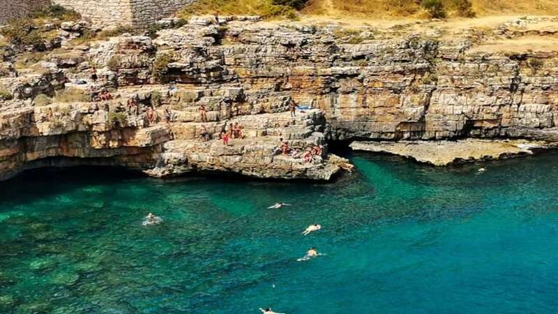 skaliste wybrzeże Apulii z opalającymi i kapiącymi się ludźmi