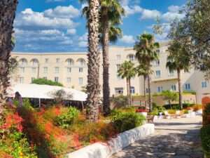 widok na główny budynek hotelu Mangia's Selinunte w otoczeniu ładnej śródziemnomorskiej roślinności