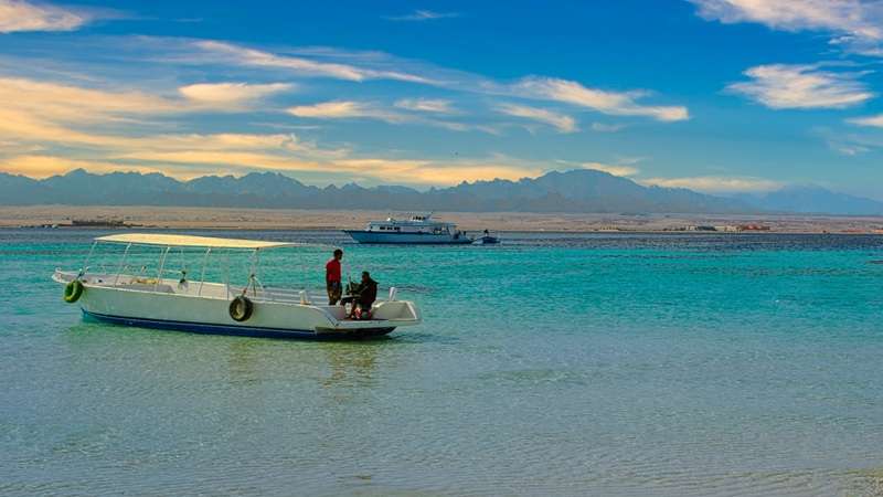łódka i jachty na płytkiej wodzie przy rafie koralowej w Egipcie